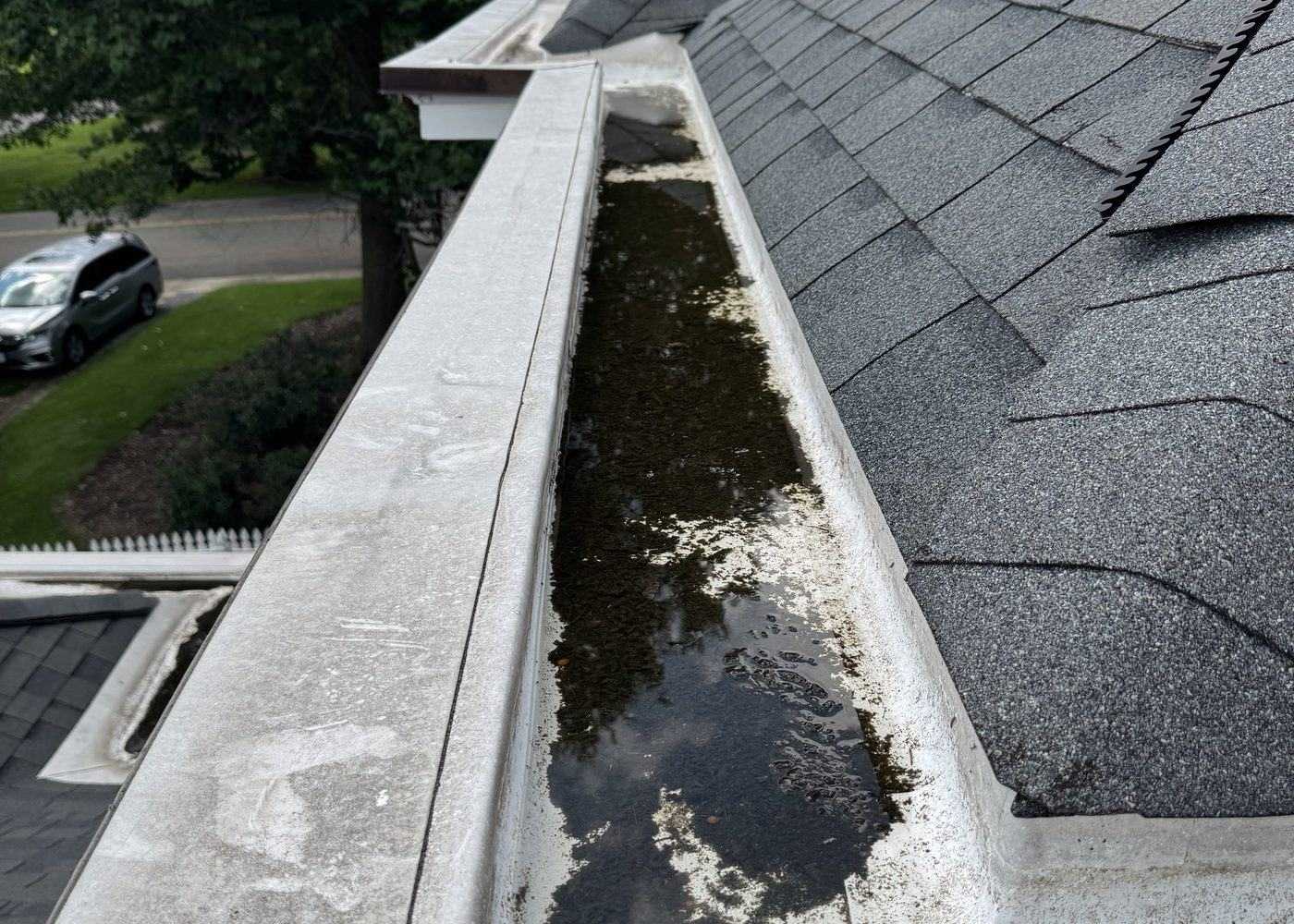 Hand-cleaning a debris-filled gutter run
